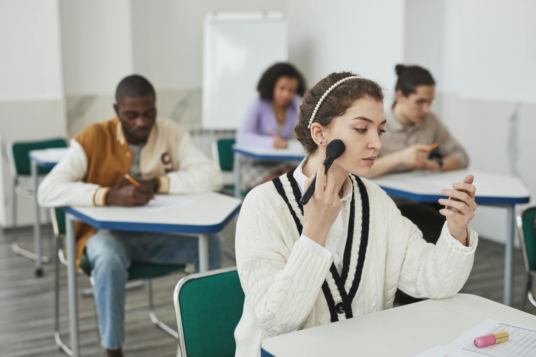 Studenci na zajęciach praktycznych z makijażu w sali lekcyjnej