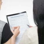 Dwie kobiety analizują formularz umowy, sprawdzając szczegóły dokumentu