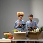 Wolontariusze pakują żywność do kartonów w siedzibie organizacji
