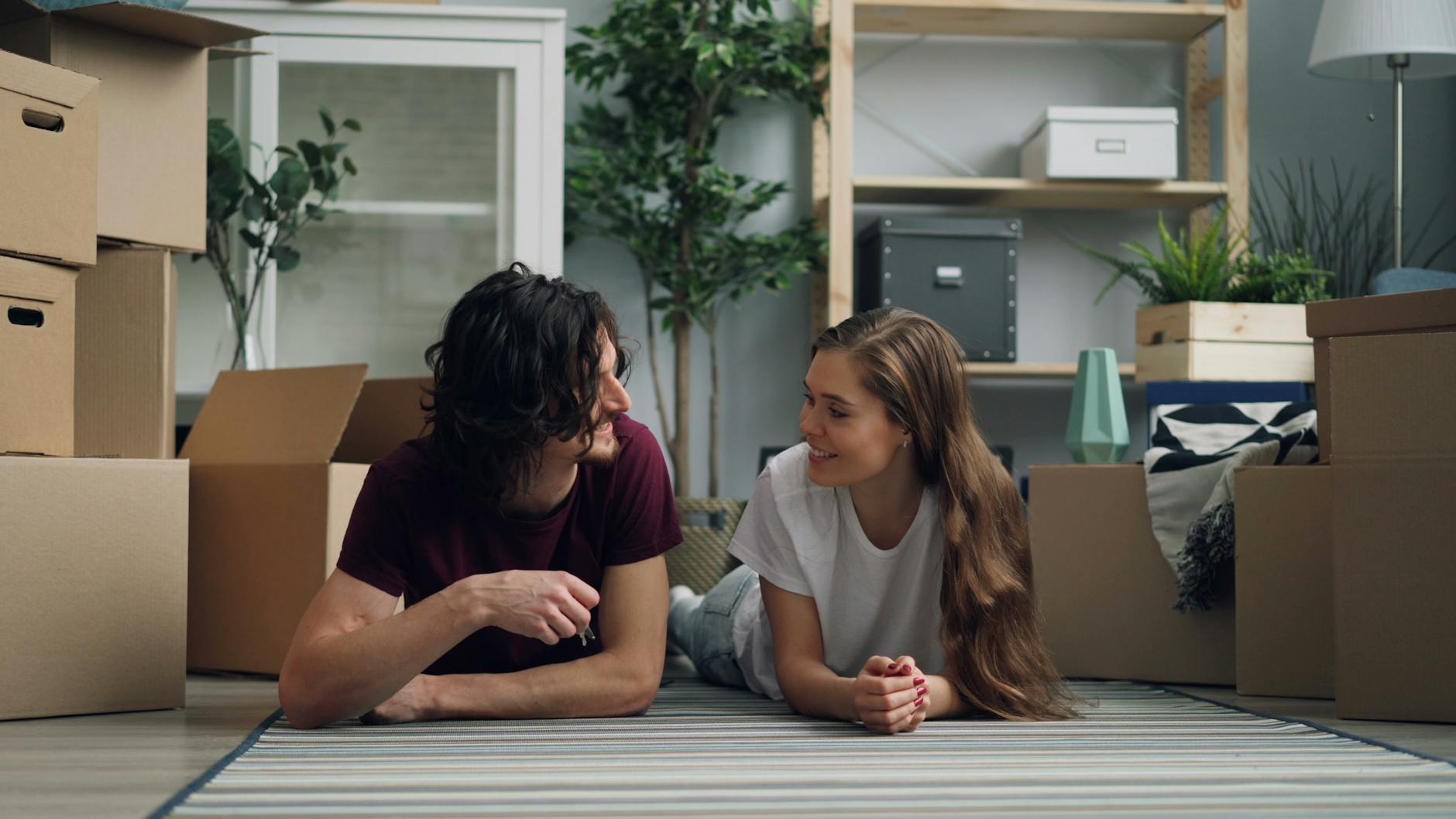 Młoda para leży na podłodze wśród kartonów w nowym mieszkaniu