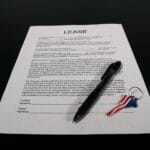 Najem lokalu dla NGO: na co uważać w umowie, kaucji i rozliczeniach mediów Umowa najmu z długopisem i brelokiem na czarnym blacie