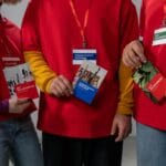 Wolontariusze w czerwonych koszulkach prezentują broszury o sztuce i ekologii