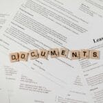 Kafle scrabble z napisem DOCUMENTS na tle umów i dokumentów