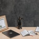 Biurko prawnika z figurką Temidy, laptopem i dokumentami