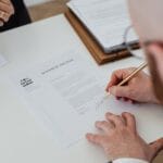 Osoba podpisująca dokument urzędowy przy biurku